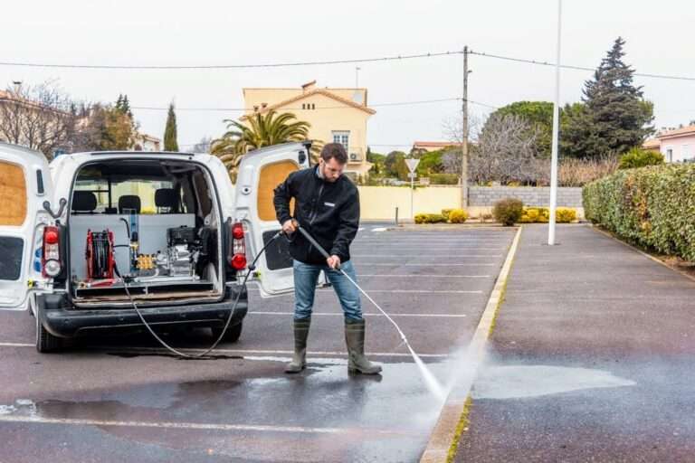 Opérateur utilisant un nettoyeur haute pression embarqué dans un utilitaire équipé d’un skid Mirage pour le nettoyage d’un parking urbain.