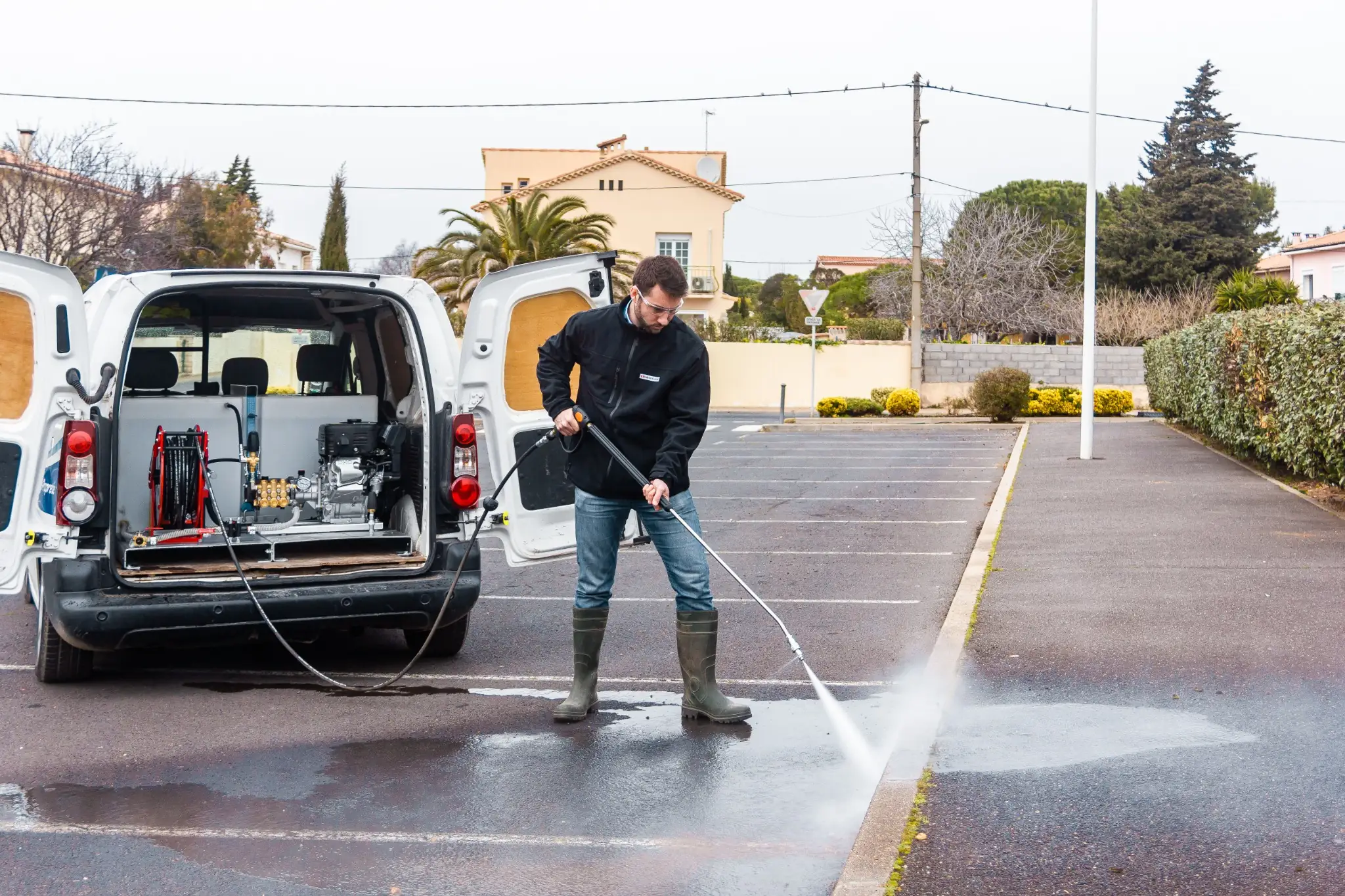 Technicien utilisant un skid de lavage haute pression MIRAGE installé dans un véhicule utilitaire pour le nettoyage de voirie.